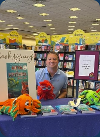 Gabriel Bietz at a book signing with Arya and Krishna books and fish toys